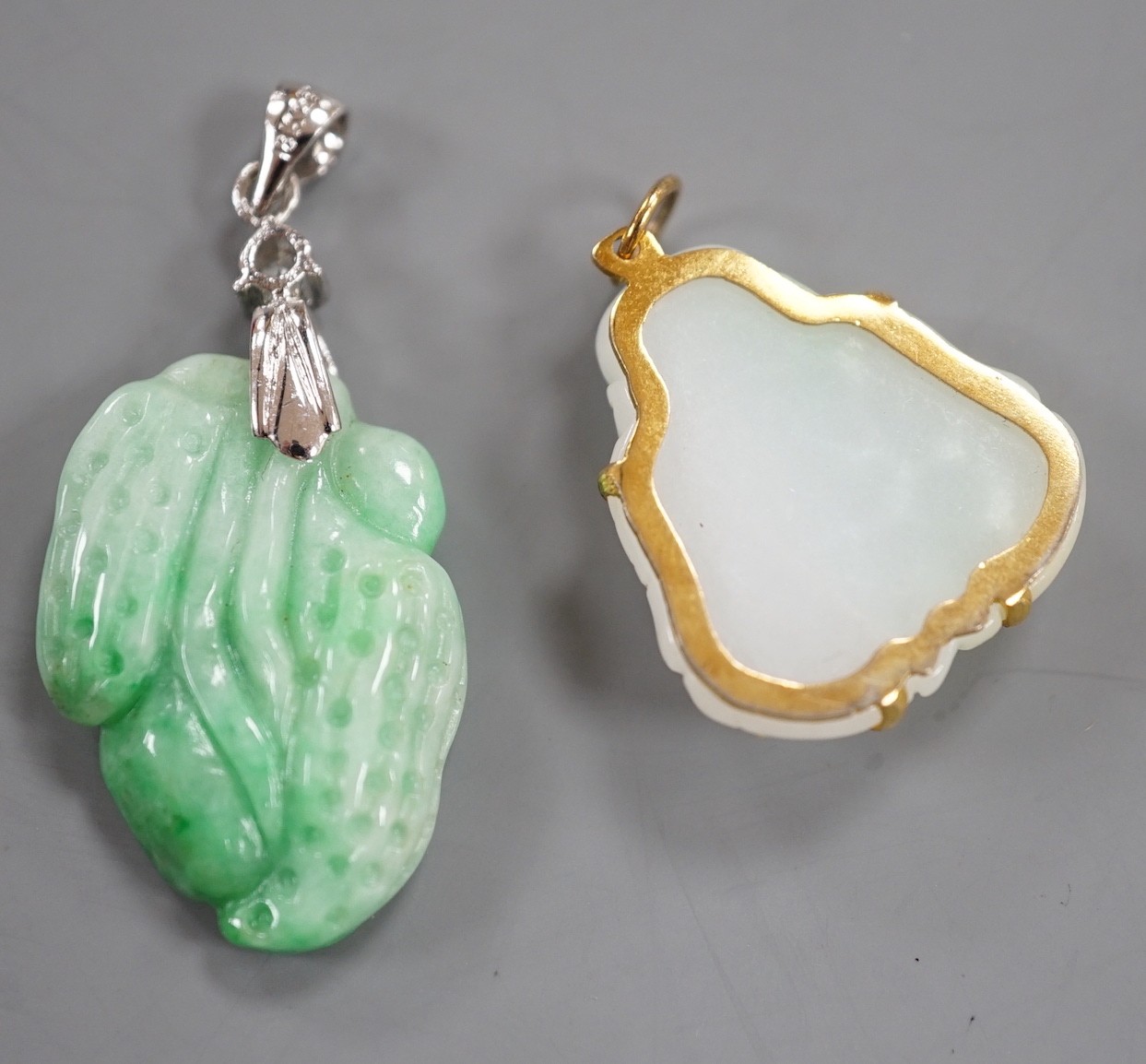 A modern 18k gold plated and simulated diamond mounted carved jade pendant, overall 39mm and a gilt metal mounted carved jade pendant.